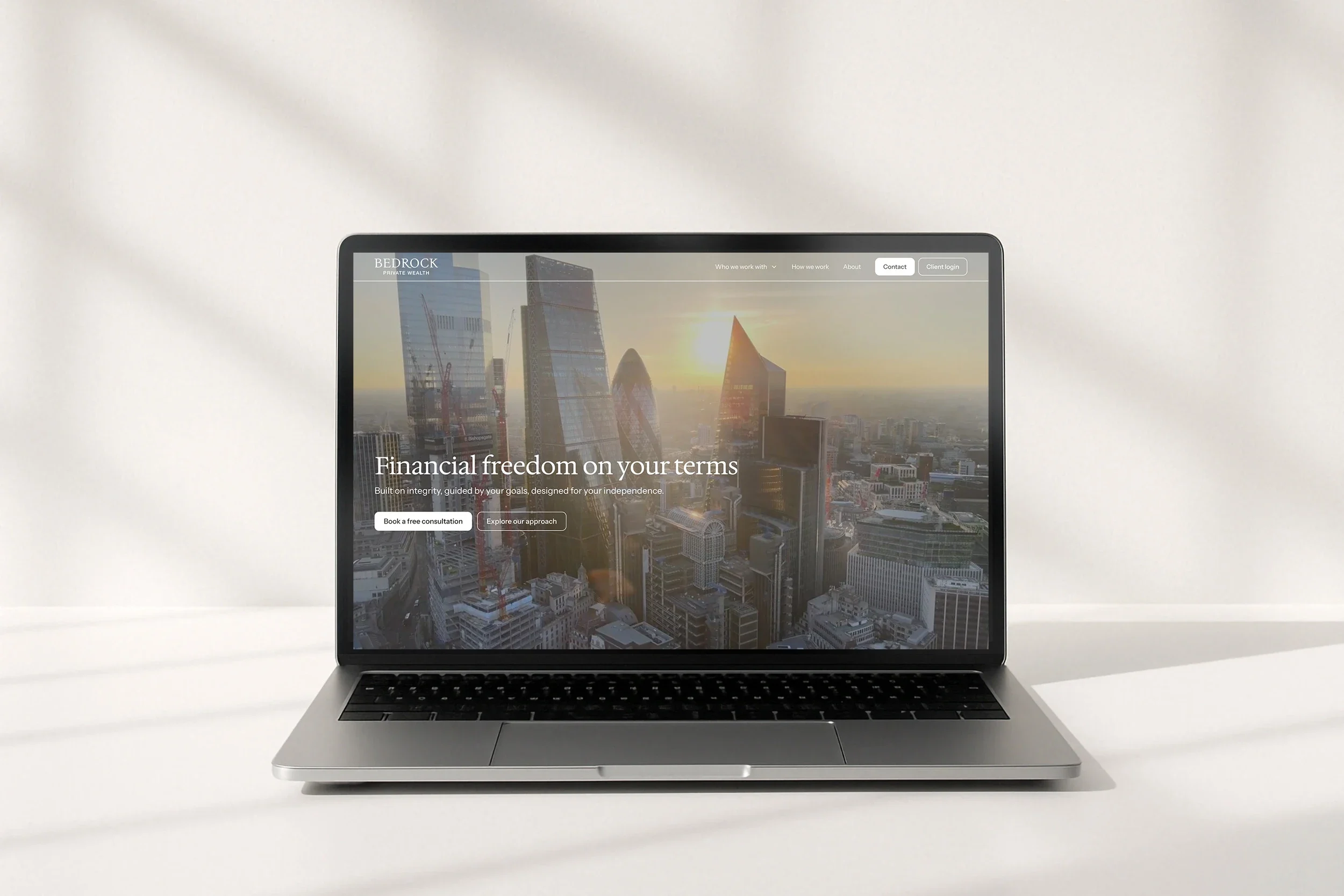 The Bedrock Private Wealth home page, 'Financial freedom on your terms', on a laptop on a white desk