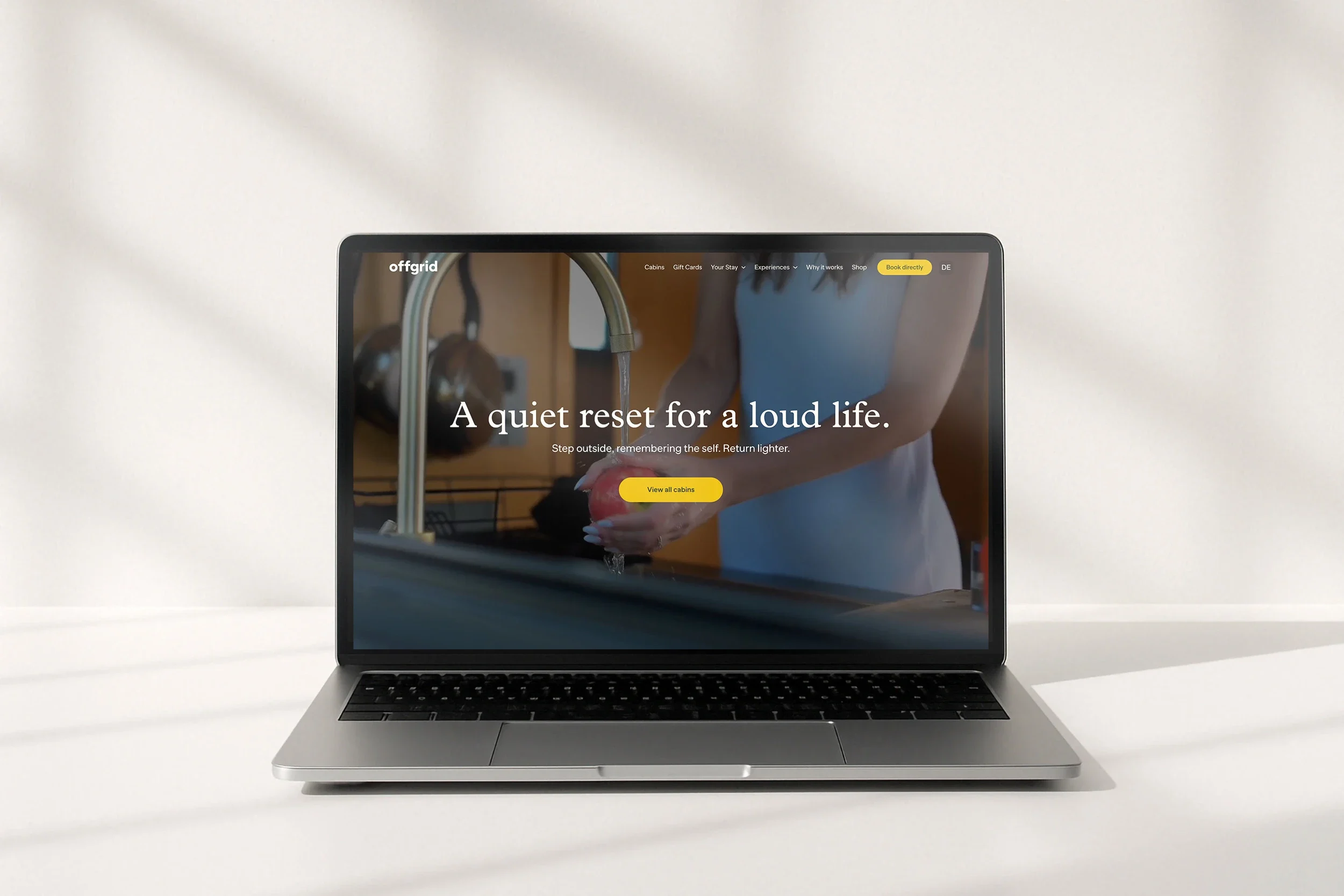 The Offgrid home page, 'A quiet reset for a loud life', on a laptop on a white desk